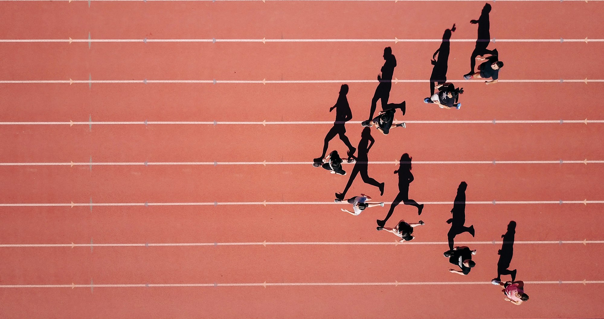 Runners in motion on a terracotta track, seen from above